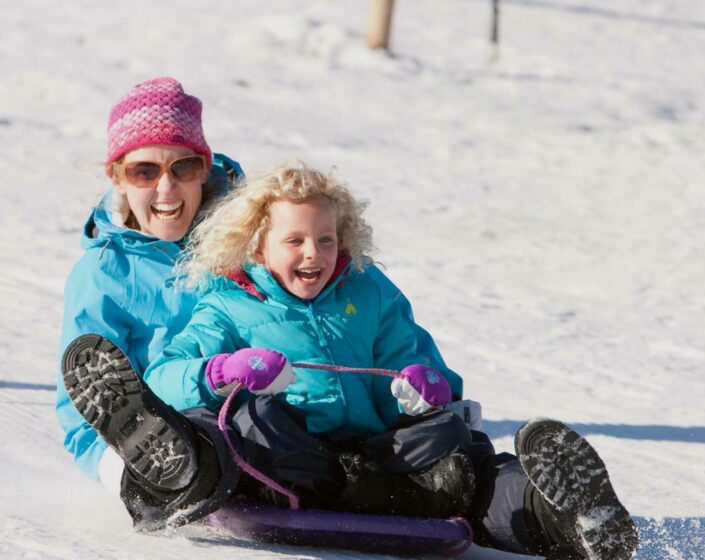 A girl tobogganing with their mother in The Lake Mountain Alpine Resort