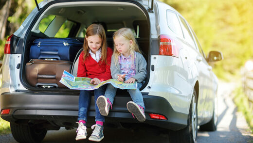 two kids sitting in the back of a car boot