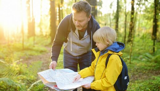 Father and son looking at a map in the forest